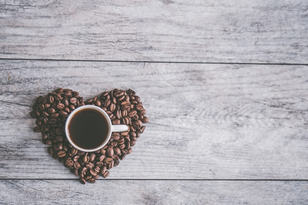 Tasse de café noir et grains de café en forme de coeur