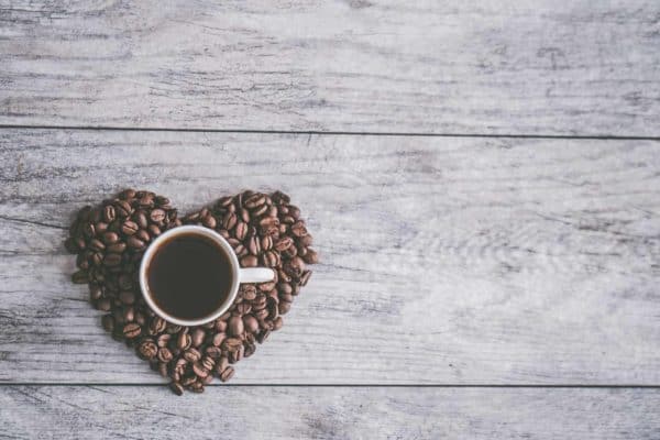 Tasse de café noir et grains de café en forme de coeur