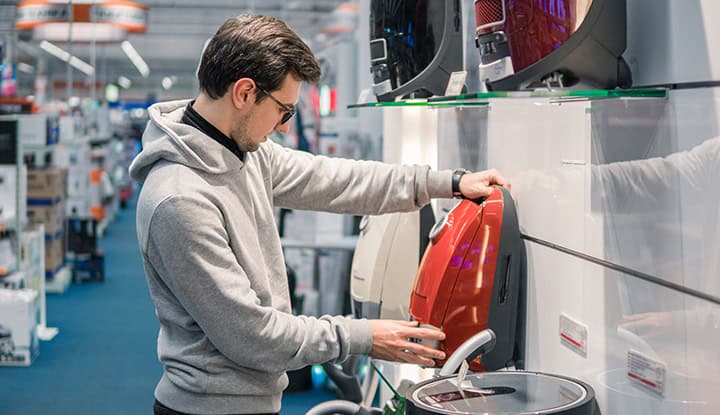 Homme Choisir Aspirateur Un homme choisit un aspirateur dans un magasin