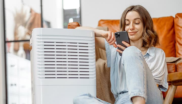 femme-climatiseur-mobile Femme à côté d'un climatiseur mobile