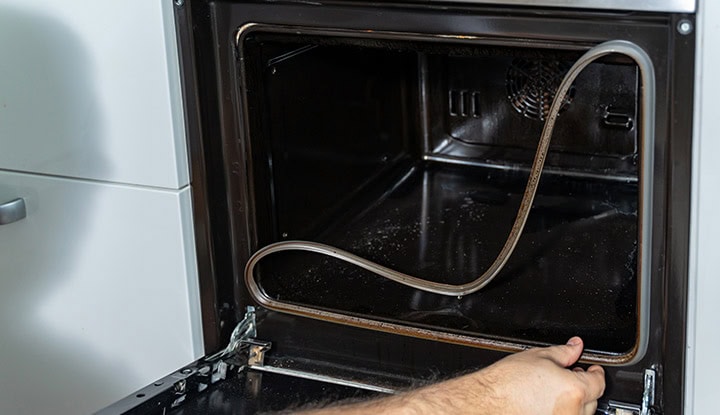 changement-joint-porte-four-défectueux Personne qui change un joint de porte défectueux d'un four